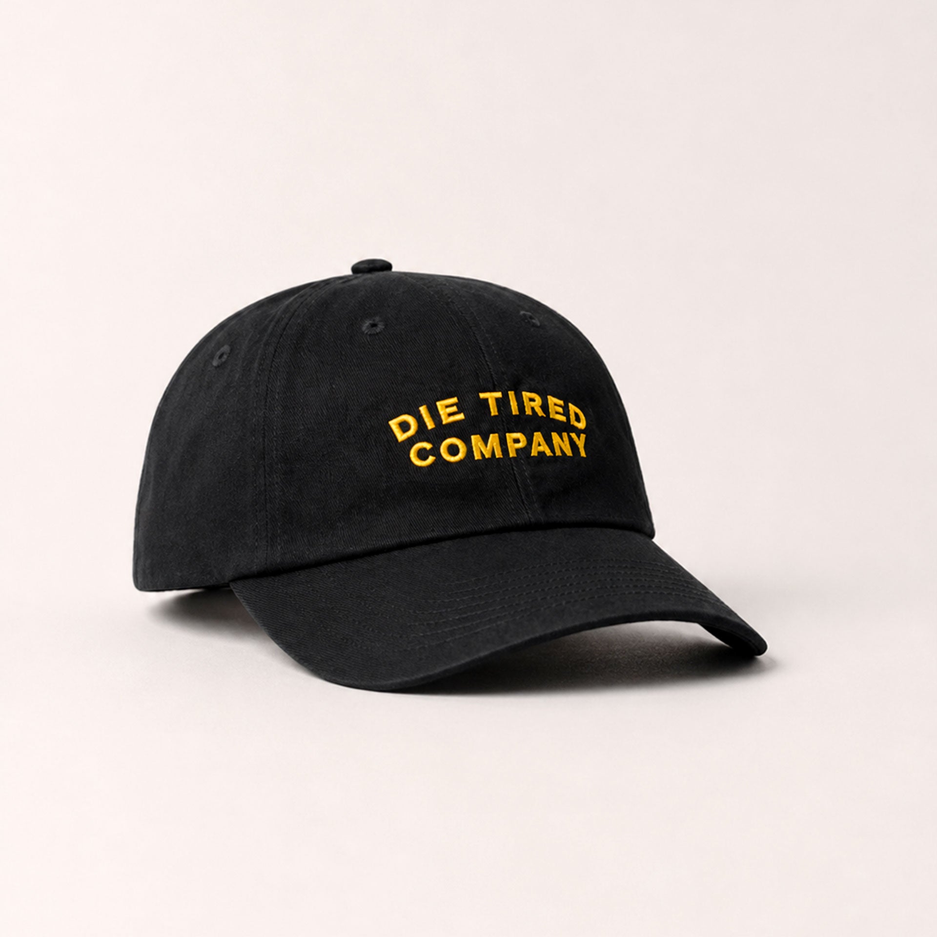 Black cotton dad hat with "Die Tired Company" in yellow embroidery on the front.