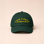 Green die tired company baseball dad cap with yellow text on a beige background